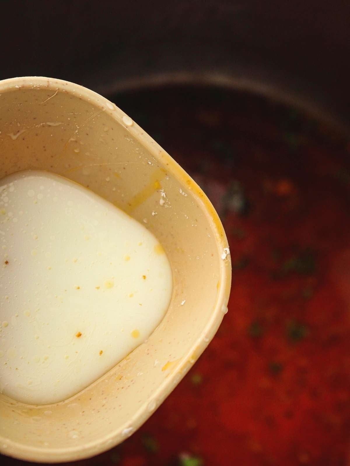 Adding the cornstarch slurry into the pot with stock.
